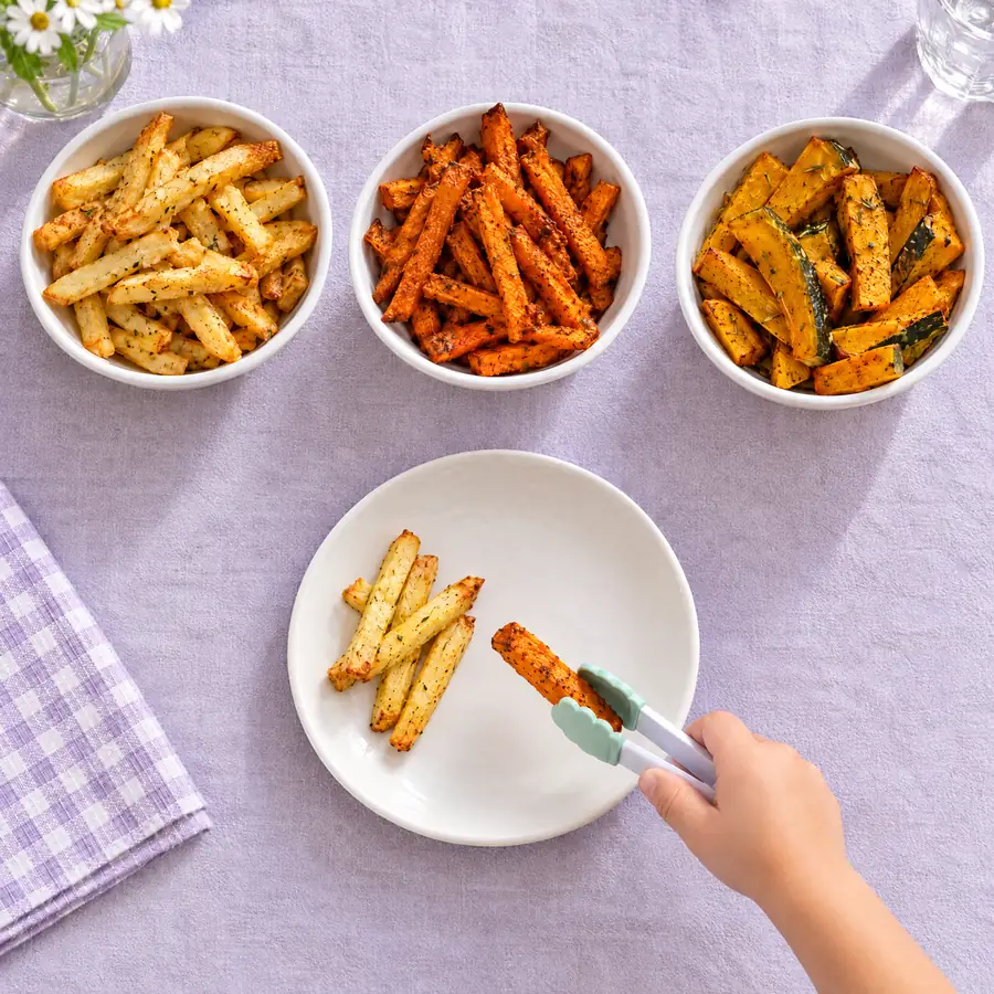 Criança se servindo sozinha de palitos de batata-doce com um pegador